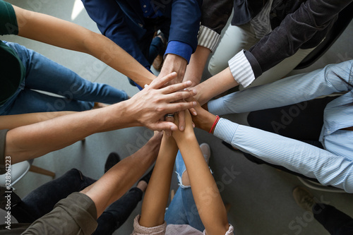 Close up top view of diverse businesspeople stack hands motivated for shared business success at briefing  multiracial colleagues engaged in teambuilding activity show unity support at office meeting