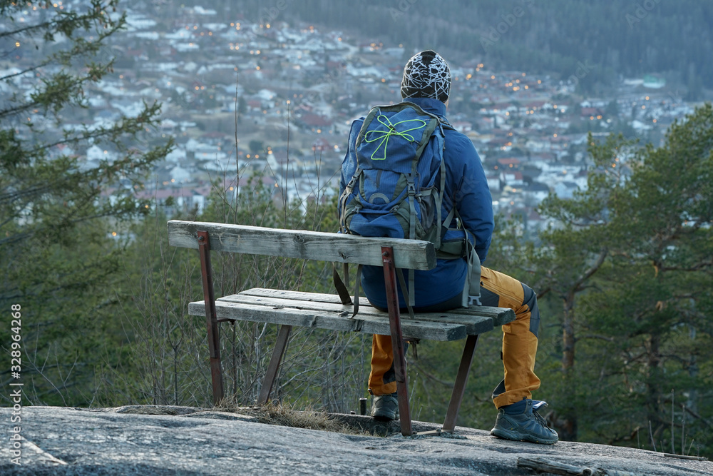A man sitting on a bench and looking at the city.