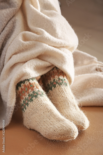 Legs of woman in knitted socks and plaid on color background
