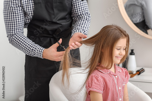 Hairdresser working with little girl in salon