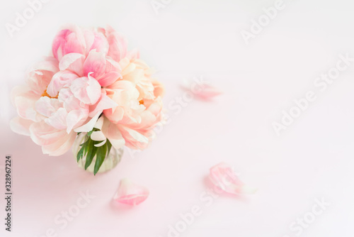Fresh bunch of pink peonies and roses in a vase on pink background. Card concept, pastel colors, copy space