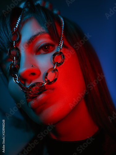 close up of a model looking at the camera with a chain in her mouth