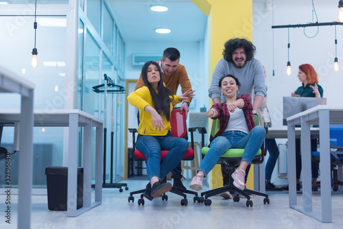 Group Of Multiethnic Young Business people with casual suit working and brainstorming together with technology computer in the modern Office, joking during brake, playing with chairs.