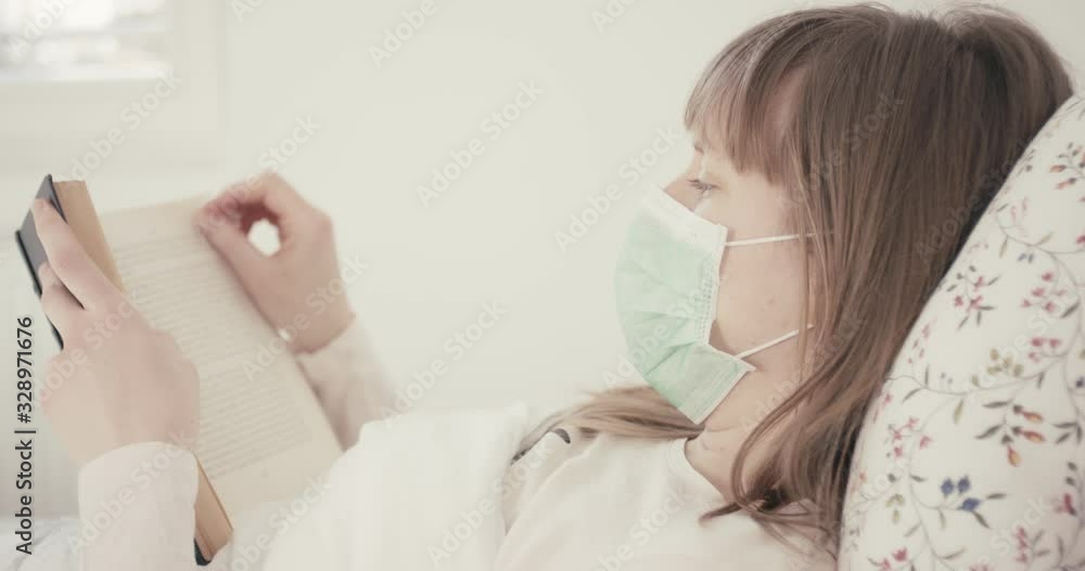 Woman with face mask reading a book coughing in bed protection virus coronavirus quarantine from behind Woman with face mask reading a book coughing in bed protection virus coronavirus quarantine from behind