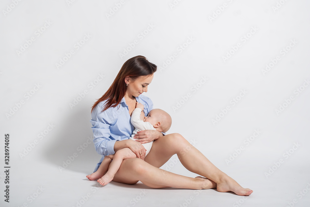 Beautiful mother feeding baby boy. Isolated on white background