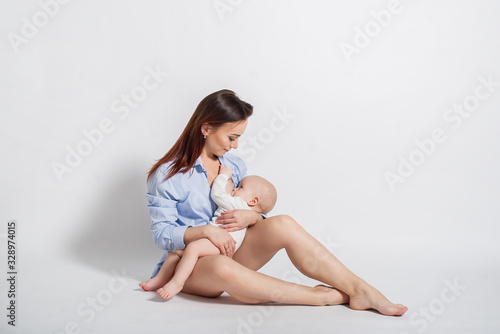 Beautiful mother feeding baby boy. Isolated on white background