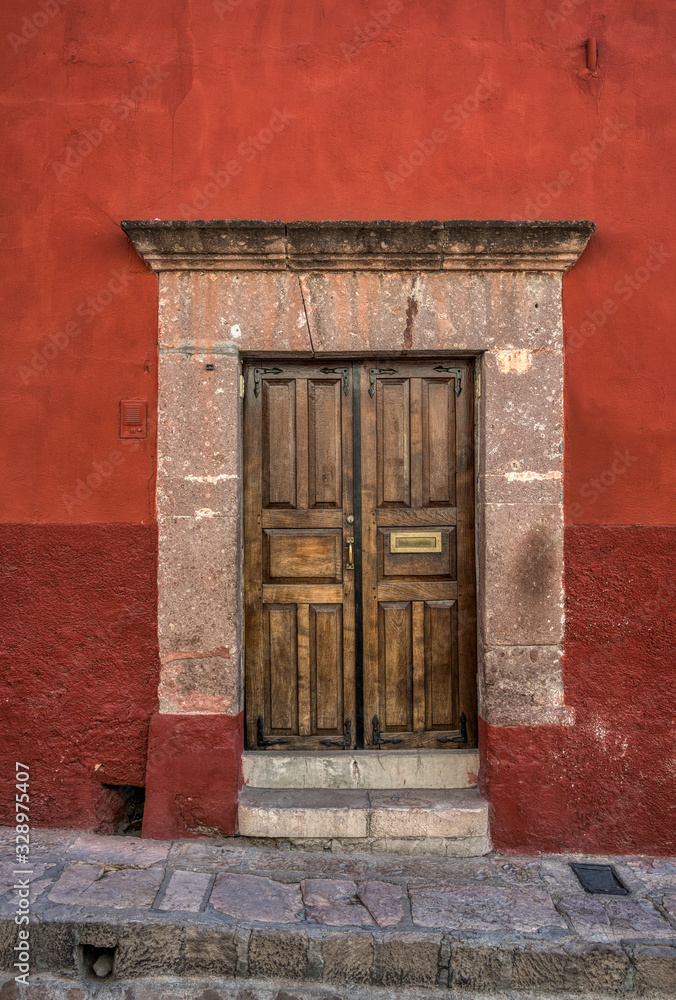 A well kept old door with a stone frame and a red wall A well kept old door with a stone frame and a red wall