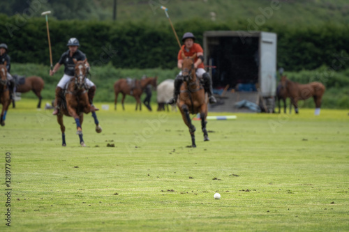 Polo players on the field. Ball on the foreground and player on their horses on the backgrounds