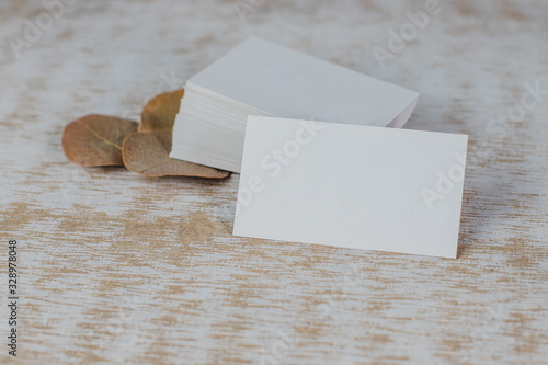 Business card mockup on light background. Corporate stationery set mockup. Business card stack on wooden background with dry leaves. Business card template. Top View and front view.