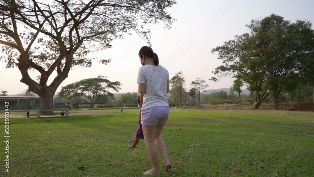 Mother and daughter playing at park during sunset hour. Slow motion