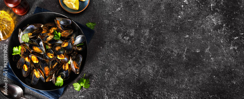 Close up of a plate with steamed mussels on black background photo