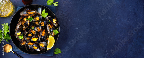 A plate with steamed mussels on dark blue background