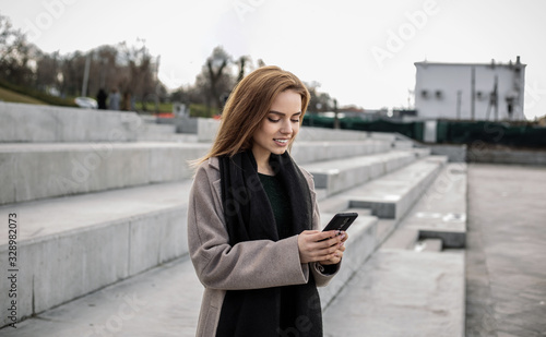 Pretty girl prints a message in a smartphone.