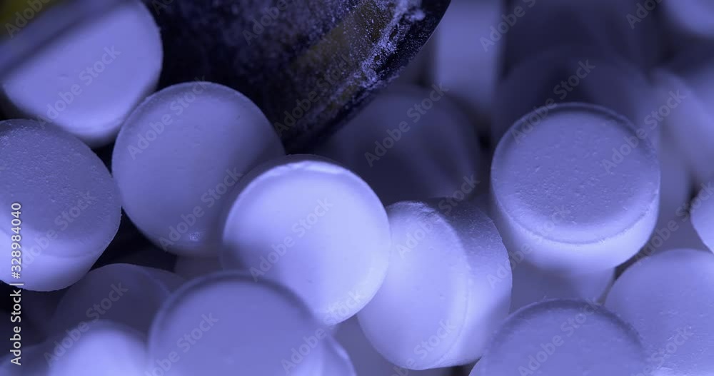Panning over pills and glass medical bottle for medicinal drugs. Blue light illuminating painkiller pills and opioids causing the opioid crisis Panning over pills and glass medical bottle for medicinal drugs. Blue light illuminating painkiller pills and opioids causing the opioid crisis