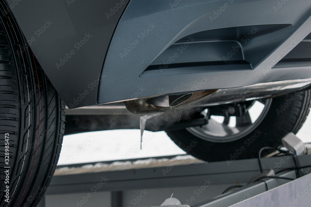 Bottom of the car is behind. View from below and side. Rubber wheels, working metal exhaust system, automobile body color Fiord. Concept of repair, warming up, tuning. Bottom of the car is behind. View from below and side. Rubber wheels, working metal exhaust system, automobile body color Fiord. Concept of repair, warming up, tuning.