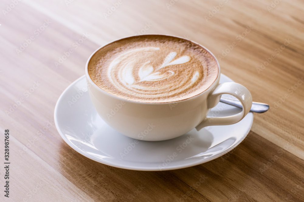 Close up white ceramic cup of latte art coffee in heart shaped isolated on wood table background. Close up white ceramic cup of latte art coffee in heart shaped isolated on wood table background.