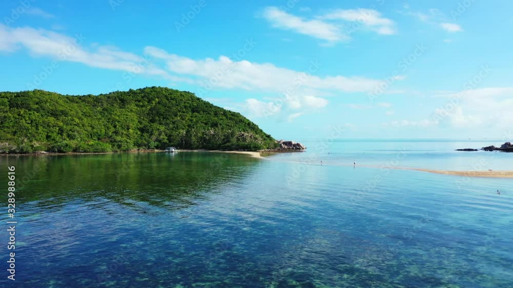 Coral reefs under calm crystal water of lagoon reflecting white clouds on blue sky over tropical island with lush vegetation in Thailand Coral reefs under calm crystal water of lagoon reflecting white clouds on blue sky over tropical island with lush vegetation in Thailand
