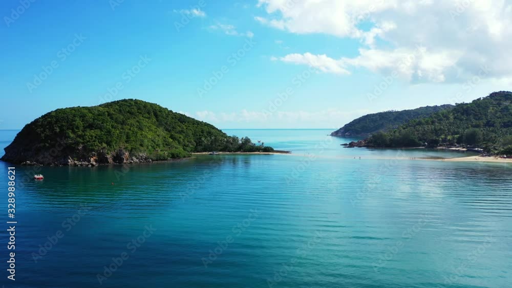 Tropical islands with lush vegetation and rocky coastline surrounded by blue turquoise seawater under bright sky with white clouds in Thailand Tropical islands with lush vegetation and rocky coastline surrounded by blue turquoise seawater under bright sky with white clouds in Thailand