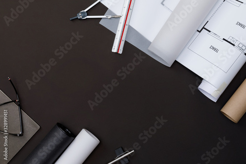 Creative flat lay of architects black table with roll blueprints, architectural project plan, engineering tools and office supplies, Workspace for new designer concept, Top view with copy space