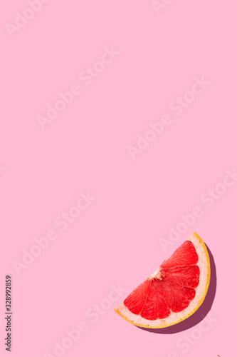 Grapefruit slice on pink background with copy space top view