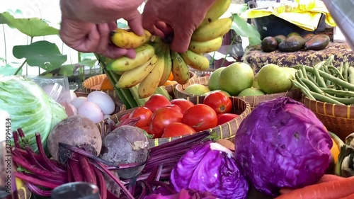 slow motion of a person taking some bananas  l at samadi Sunday market, Bali. Fruit, vegetables and some bottles. photo