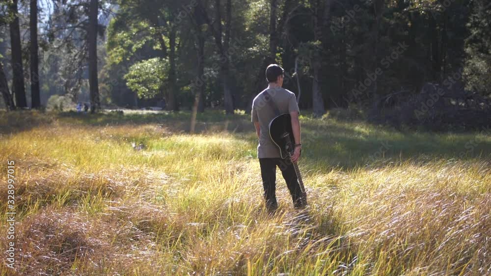Cinematic Slowmotion of Male Standing in Grass Field With Guitar. Yosemite Valley National Park California USA Cinematic Slowmotion of Male Standing in Grass Field With Guitar. Yosemite Valley National Park California USA