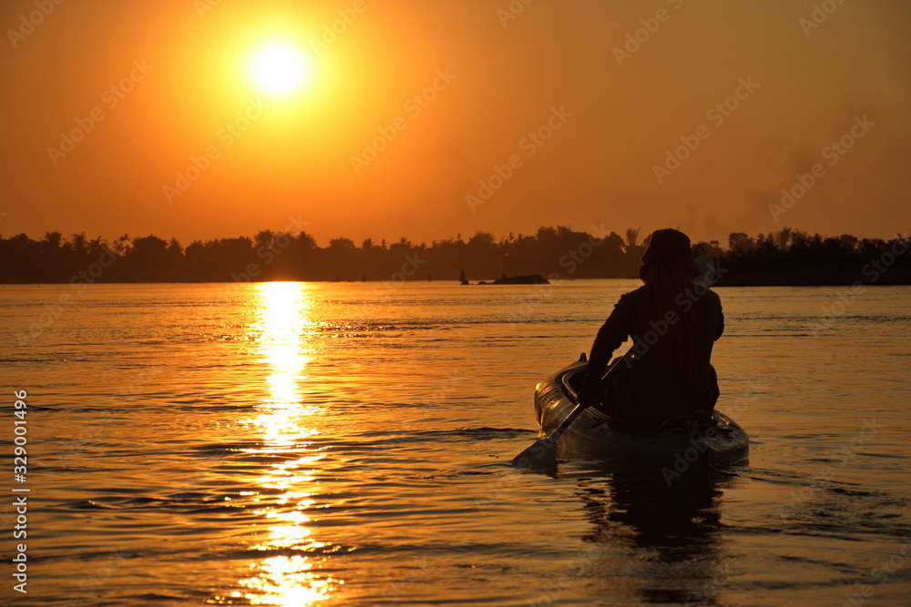 Man paddling in kayak during sunset on Mekong river