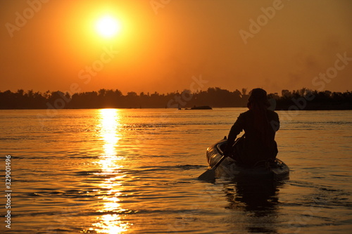 Man paddling in kayak during sunset on Mekong river
