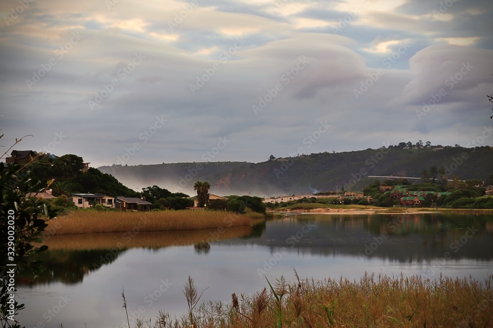 Cloudy sky over the Touws River mouth with reeds in the foreground and houses on the banks of the river