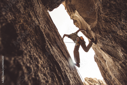 Fototapet Rock climber in a canyon, pressing between two walls.