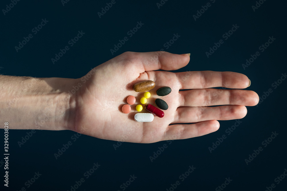 Close-up shot of a hand holding color pills on blue background. Close-up shot of a hand holding color pills on blue background.