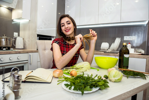 charming girl prepares a salad of different vegetables and greens flavored with olive oil for a healthy lifestyle.