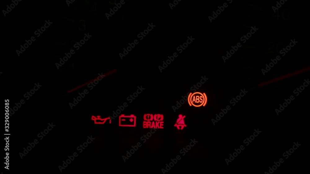 Red and yellow car warning signs on modern car dashboard on black background. Red warning car signs on dashboard, close-up view.