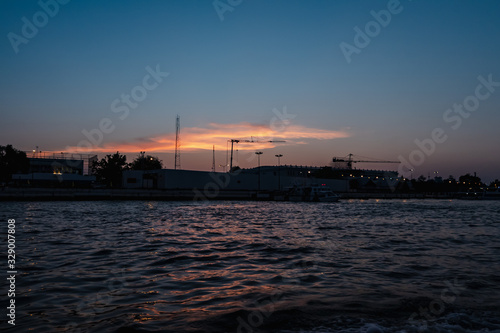 Sunrise or sunset view of Chao Phraya River , Bangkok, Thailand . Shows water transport. reflective of the sun. Image contain certain grain or noise and soft focus