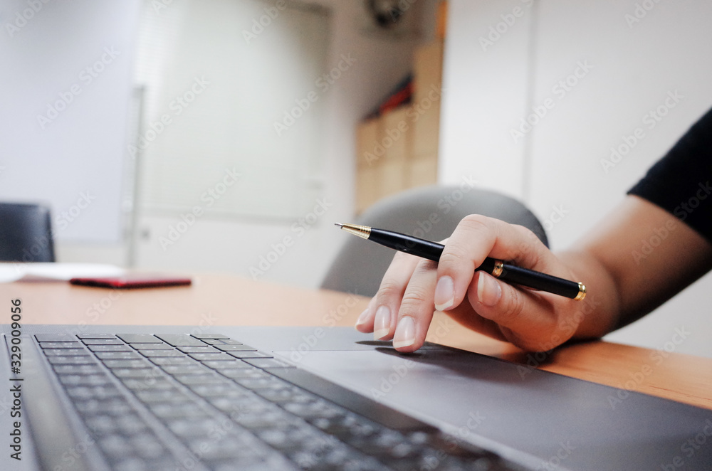 freelancer working on laptop computer and holding pen freelancer working on laptop computer and holding pen