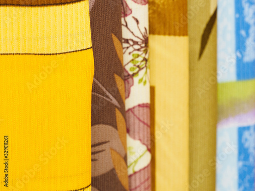 Multi-colored fabrics with a pattern hang for sale in a store. The concept of fashionable clothes and interior