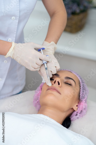 Cosmetologist wearing gloves doing mesotherapy for patient