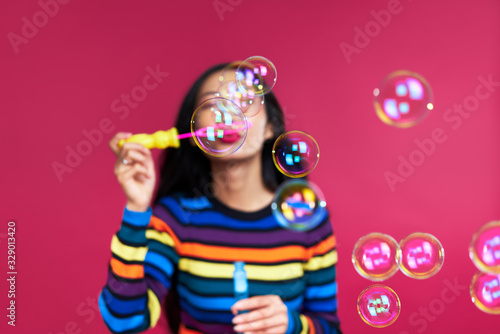 Happy beautiful woman blowing soap bubbles