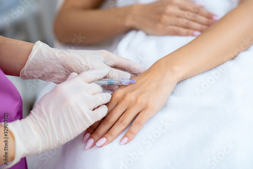 Close up of beauty doctor making injection into arm