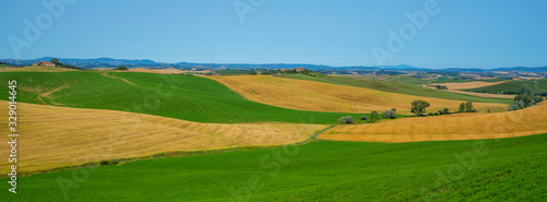 View of a sunny day in the Italian rural landscape. Unique Tuscany landscape in summer time. Wave hills, colorful fields, cypresses trees and sky.