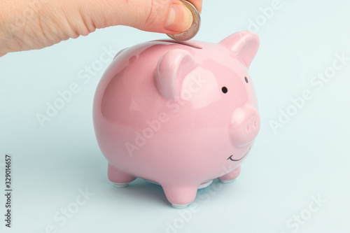 Piggy Bank on white background, space for text. A woman's hand whith coin. Finance, saving money