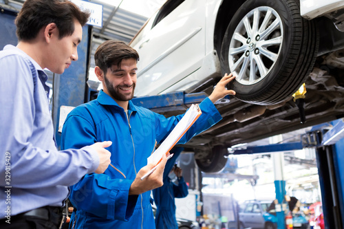 A mechanic and customer look at paper. service car in garage is paper checklist car. service car, repair, maintenance concept.Technician doing the checklist for repair machine a car in the garage.