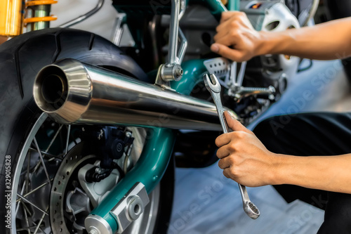 Image is Close up,People are repairing a motorcycle Use a wrench and a screwdriver to work.