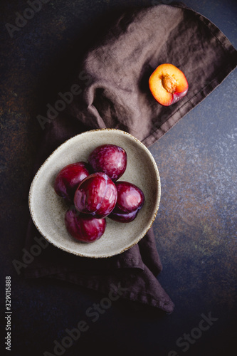 High angle view of fresh purple plum on a dark linen. Food photography still life.