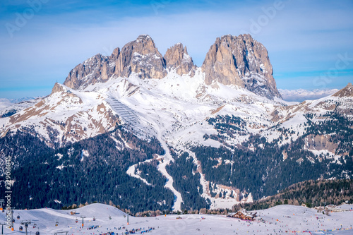 View of a ski resort piste with people skiing in Dolomites in Italy. Ski area Belvedere. Canazei, Italy