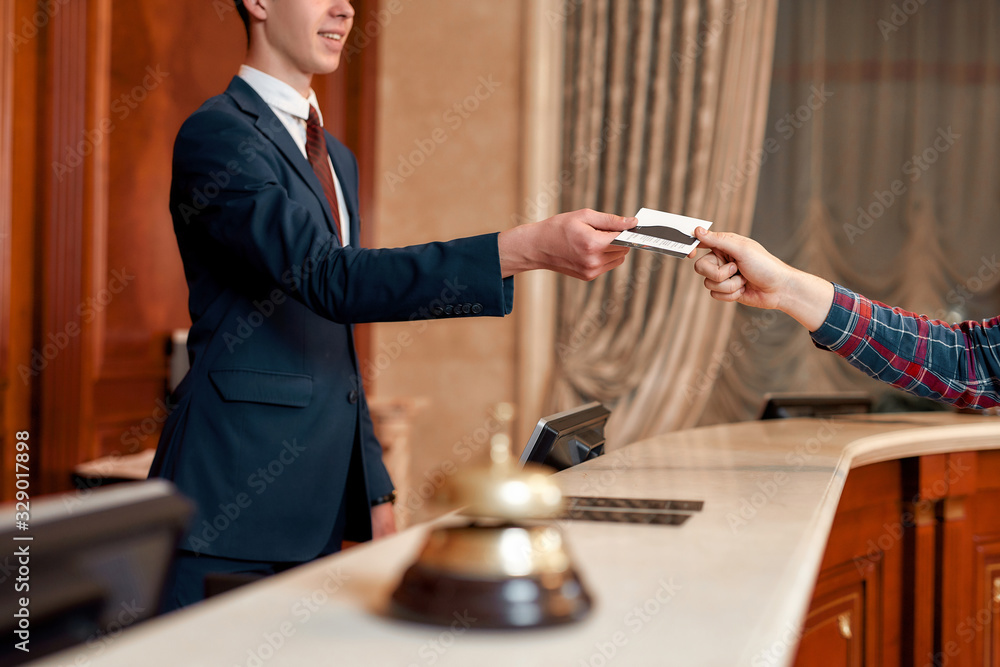 Special offers. Cropped shot of young executive at the reception desk of a hotel working, giving privileged personal card to a guest