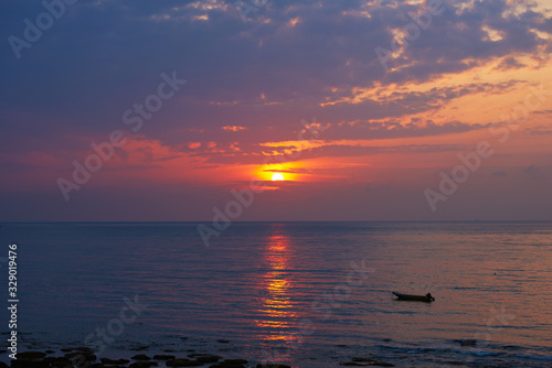 Landscape of paradise tropical island beach  sunrise shot. Beautiful sunrise over the tropical sea. Old fisherman boat at the distance.