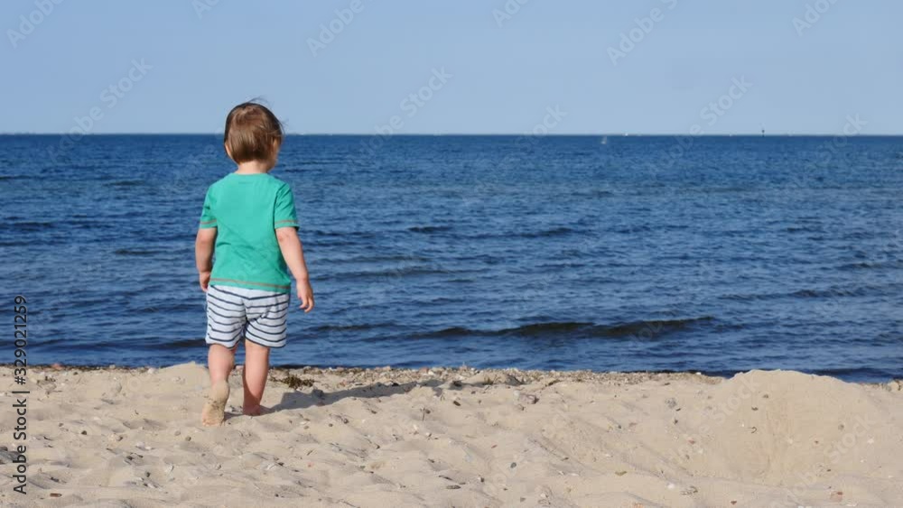 Little child boy walking barefoot on sand, playing on beach. Slow motion Little child boy walking barefoot on sand, playing on beach. Slow motion