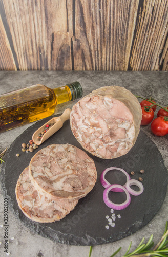 Фотография Headcheese is a pressed pressed piece of meat cut on black slate