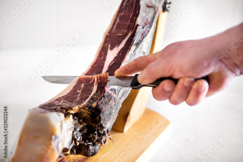 Fototapeta Naklejka Na Ścianę i Meble -  Close-up on male hand slicing Jamon